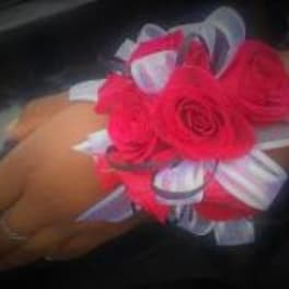 Hand corsage with bright pink roses and white ribbon