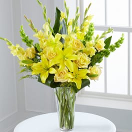 Yellow lilies and roses arranged in a clear glass vase