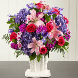 Bouquet of pink lilies, red roses, and purple hydrangeas in a white vase