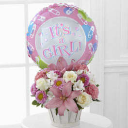 Pink and white flower arrangement with a "It's a Girl!" balloon