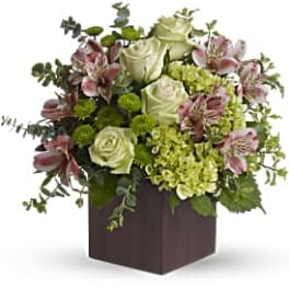 Green and pink floral arrangement in a dark square box
