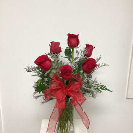 Red roses in a clear glass vase with a red ribbon bow