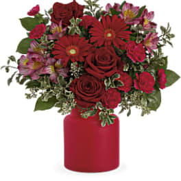 Red roses and pink flowers in a red vase