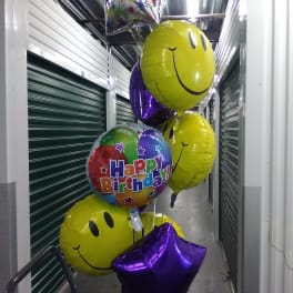 Birthday balloons with smiley faces and a "Happy Birthday" balloon