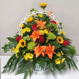 Mixed bouquet with orange lilies, red roses, and yellow daisies in a white basket