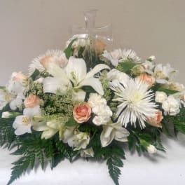 White floral arrangement with lilies and roses in a glass cross vase