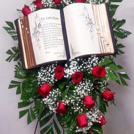 Standing floral tribute with red roses around an open book display