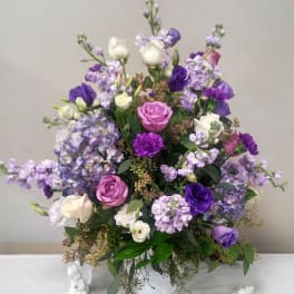 Purple and white floral arrangement in a white vase
