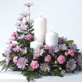 Floral arrangement with white candles and pink and lavender flowers