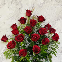 Basket arrangement of red roses with greenery and white filler flowers
