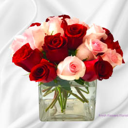 Red and pink roses arranged in a clear square vase
