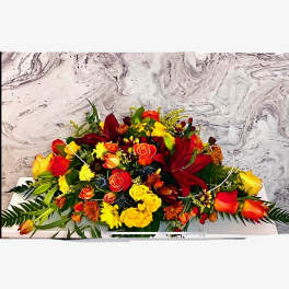 Long low arrangement of red, yellow, and orange flowers on a white base