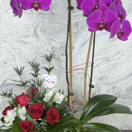Purple orchids and red roses in a wooden box with a heart pick