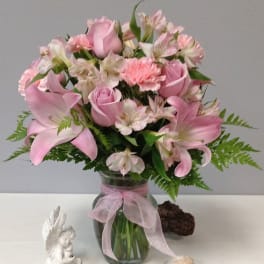 Pink lilies and roses in a glass vase with a ribbon