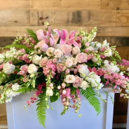 Large pink and white floral arrangement with roses and lilies on a white pedestal