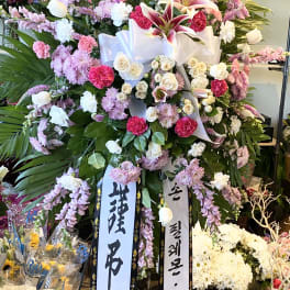 Large standing floral spray with pink, white, and purple flowers and ribbon streamers