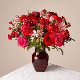 Red and pink rose bouquet in a dark glass vase