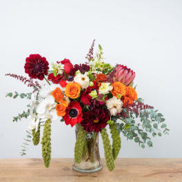 Mixed bouquet in a glass vase with red, orange, white, and pink blooms