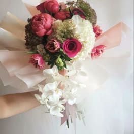 Hand-tied bouquet of pink and white flowers with trailing white orchids