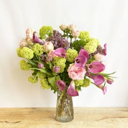 Bouquet of pink calla lilies, roses, and green hydrangeas in a glass vase
