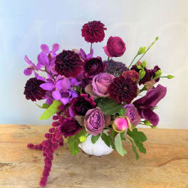 Purple and pink floral arrangement in a white vase
