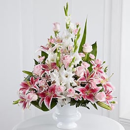 Pink and white floral arrangement in a white pedestal vase