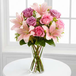 Pink roses and lilies arranged in a clear glass vase