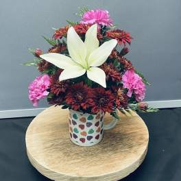Bouquet of red and pink flowers in a heart-pattern mug