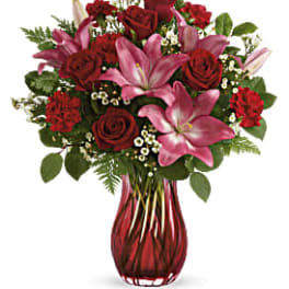 Red roses and pink lilies in a red glass vase