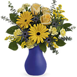 Yellow and cream flower arrangement in a blue vase