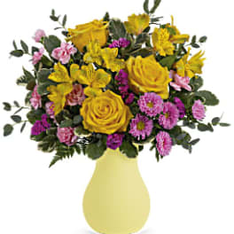 Yellow roses and pink flowers in a pale yellow vase