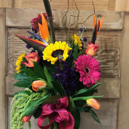 Tall tropical bouquet with sunflowers, gerbera daisies, tulips, and bird of paradise in a glass vase