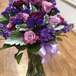 Bouquet of pink and purple flowers in a glass vase with a lavender ribbon
