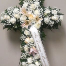White floral funeral cross with a memorial ribbon