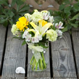 Bouquet of yellow and white flowers in a glass jar with a ribbon