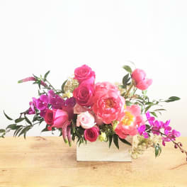 Pink and purple floral arrangement in a white box