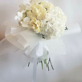 White bridal bouquet with hydrangeas and orchids wrapped in ribbon
