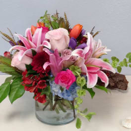 Pink lilies and roses arranged in a glass vase