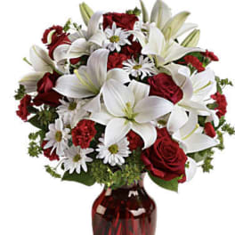 Red roses and white lilies arranged in a red glass vase