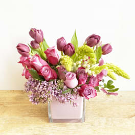 Pink and purple tulips and roses in a square glass vase