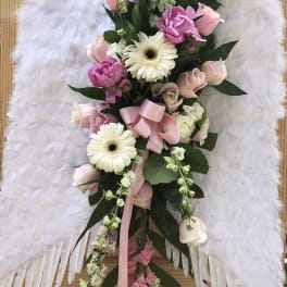White angel wings with a pink and white floral spray on a stand