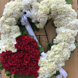 Heart-shaped floral wreath with white hydrangeas and red roses on a stand