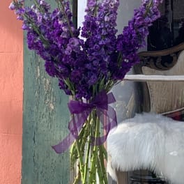 Purple flower bouquet in a clear glass vase with a ribbon bow