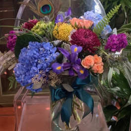 Colorful mixed bouquet in a clear glass vase with a teal ribbon