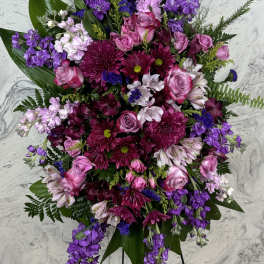 Large standing floral spray with pink and purple flowers on a black easel