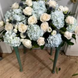 Blue hydrangeas and white roses arranged on a small table.