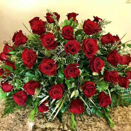 Low elongated arrangement of red roses in a dense, dome-shaped display