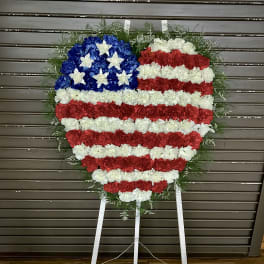 Heart-shaped standing floral wreath in red, white, and blue styled like the American flag