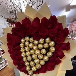 Heart-shaped bouquet of red roses with gold-wrapped chocolates in the center