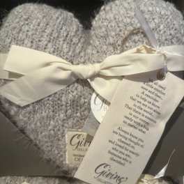 Two knitted heart ornaments tied with cream ribbons in a gift box
